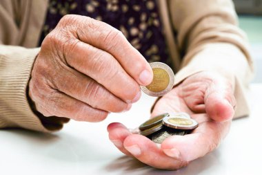 Retired elderly woman counting coins money and worry about monthly expenses and treatment fee payment.