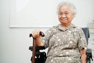 Hastanede tekerlekli sandalyede oturan Asyalı yaşlı kadın engelli hasta, tıbbi konsept..