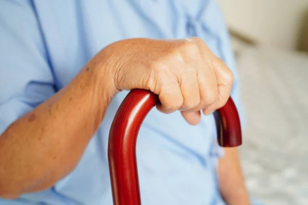 亚洲老年残疾妇女患者手握手杖 双手皱巴巴地躺在医院里 — 图库照片
