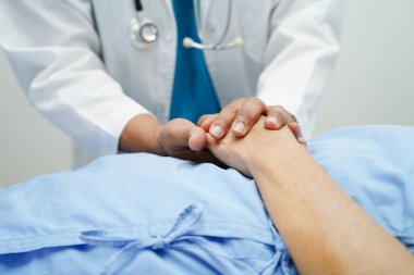 Doktor el ele tutuşuyor Asyalı yaşlı kadın hasta, hastanede yardım ve bakım.