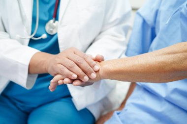 Doktor el ele tutuşuyor Asyalı yaşlı kadın hasta, hastanede yardım ve bakım.