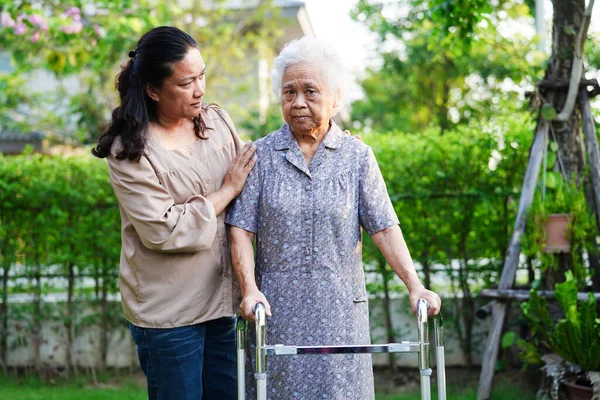 stock image Caregiver help Asian elderly woman disability patient walk with walker in park, medical concept.