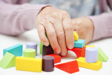 Yaşlı Asyalı kadın bunama ve Alzheimer hastalıklarını önlemek için beyin eğitimi oyunu oynuyor..