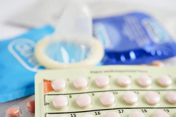 Pregnancy test with birth control pills and condom for female on calendar, ovulation day.
