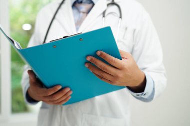 Asyalı doktor, hastaları tedavi etmek için araştırma yöntemi ve teknikle ilgili belgeleri inceliyor..