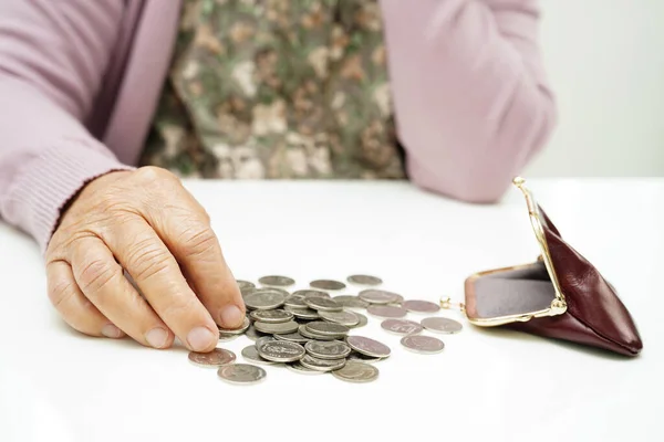 Retired elderly woman counting coins money and worry about monthly expenses and treatment fee payment.