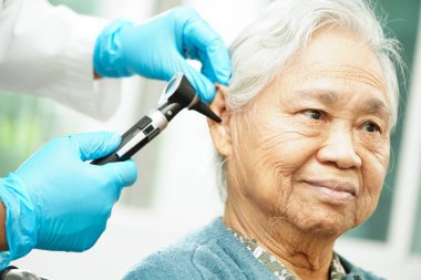Otolaryngologist ya da ENT hekim doktoru yaşlı hasta kulağını otoskopla muayene ediyor, işitme sorunu var.. 