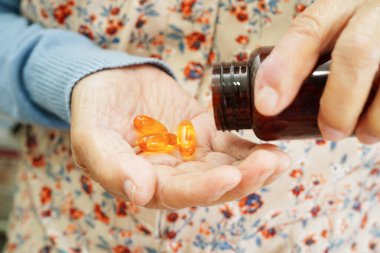 Asian elderly woman holding pill drug in hand, strong healthy medical concept. 