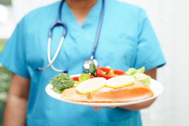 Asyalı Beslenme Uzmanı hastalar için sağlıklı yiyecekler, beslenme ve vitamin tutuyor..