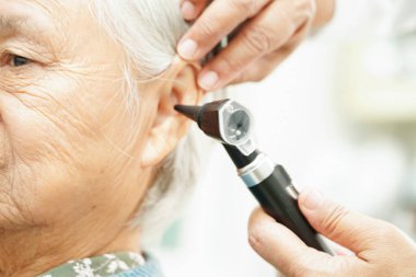 Otolaryngologist ya da ENT hekim doktoru yaşlı hasta kulağını otoskopla muayene ediyor, işitme sorunu var.. 