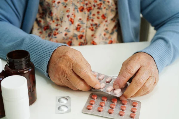 Asian elderly woman holding pill drug in hand, strong healthy medical concept.