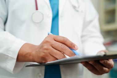 Doktor kontrol ediyor ve teşhis ilacını hastanedeki hastaların dosyalarına not ediyor..