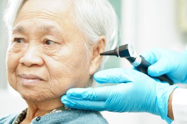 Otolaryngologist ya da ENT hekim doktoru yaşlı hasta kulağını otoskopla muayene ediyor, işitme sorunu var..