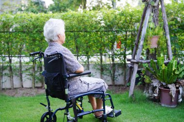 Parkta tekerlekli sandalyede oturan Asyalı yaşlı kadın engelli hasta, tıbbi konsept..