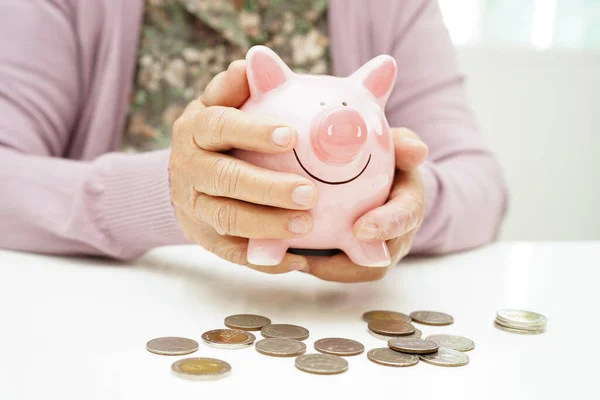 Retired elderly woman counting coins money with piggy bank and worry about monthly expenses and treatment fee payment.