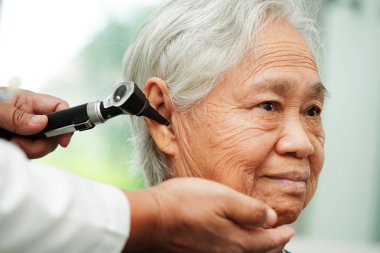 Otolaryngologist ya da ENT hekim doktoru yaşlı hasta kulağını otoskopla muayene ediyor, işitme sorunu var.. 