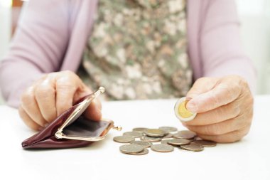 Retired elderly woman counting coins money and worry about monthly expenses and treatment fee payment.