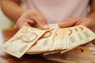 Tayland baht banknotlarını sayan Asyalı bir kadın, elinde para, yatırım ekonomisi, muhasebe ve bankacılık.