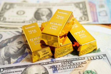 Gold bars on US dollar banknote money, finance trading investment business currency concept. 