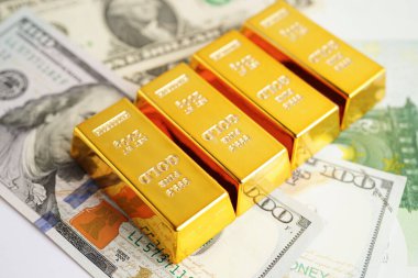 Gold bars on US dollar banknote money, finance trading investment business currency concept. 