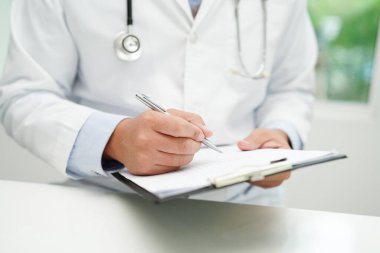 Asyalı doktor, hastaları tedavi etmek için araştırma yöntemi ve teknikle ilgili belgeleri inceliyor..