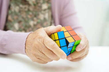 Bangkok, Tayland - 15 Mayıs 2022 Asyalı yaşlı kadın bunama ve Alzheimer hastalıklarını önlemek için Rubik küp oyunu oynuyor