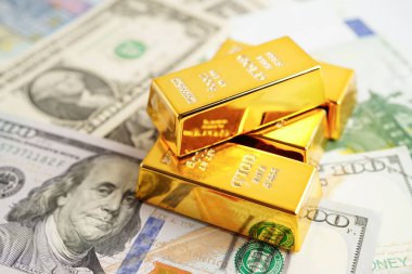 Gold bars on US dollar banknote money, finance trading investment business currency concept. 