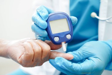 Diyabet tedavisinde kan şekeri seviyesini kontrol etmek için dijital glikoz ölçer kullanan Asyalı doktor.