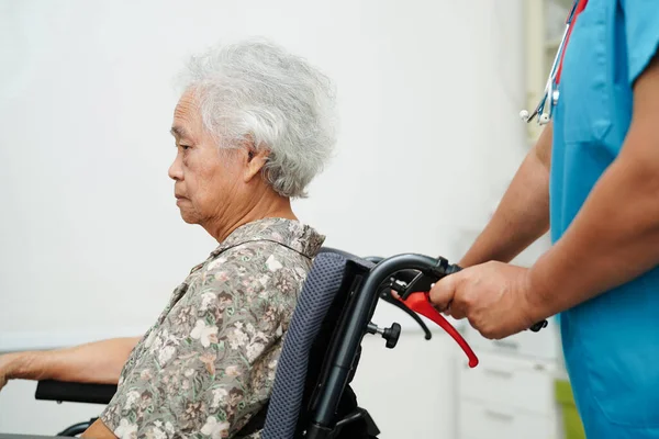 Doctor help Asian elderly woman disability patient sitting on wheelchair in hospital, medical concept.