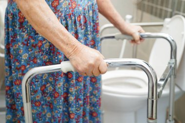 Asyalı yaşlı kadın hasta tuvalette tuvalet desteğini, tırabzan emniyet çubuğunu, hemşire hastanesinde güvenliği kullanıyor..