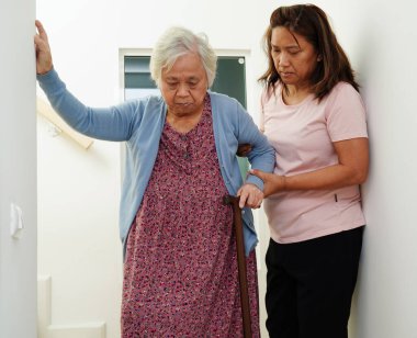 Asyalı son sınıf öğrencisi kadın, bakıcıya destek için baston kullanıyor merdivenlerden inerken kaza, kayıp düşme gibi şeyleri engelliyor..