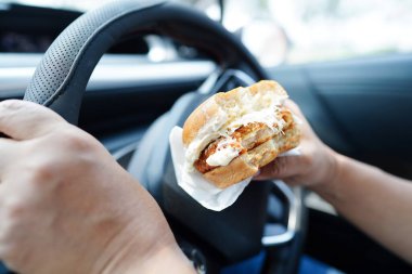 Asyalı kadın sürücü arabada hamburger yiyip, tutar, tehlikeli ve kaza riskini göze alır..