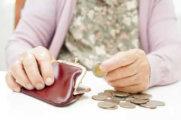 Retired elderly woman counting coins money and worry about monthly expenses and treatment fee payment.
