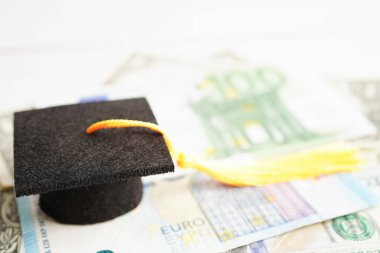 Avrupa ve ABD doları üzerindeki mezuniyet şapkası para, eğitim ücreti öğrenim öğrenimi öğretim konsepti.