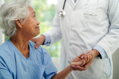 Doktor el ele tutuşuyor Asyalı yaşlı kadın hasta, hastanede yardım ve bakım.