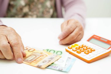 Retired elderly woman counting coins money and worry about monthly expenses and treatment fee payment.