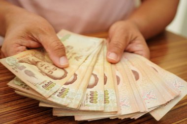 Tayland baht banknotlarını sayan Asyalı bir kadın, elinde para, yatırım ekonomisi, muhasebe ve bankacılık.