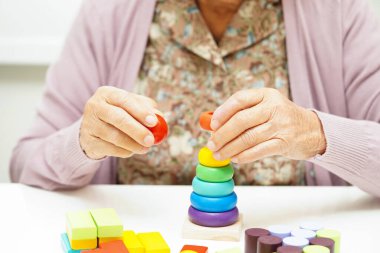 Asian elderly woman playing puzzles game for treatment dementia prevention and Alzheimer disease. clipart