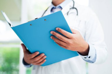 Asyalı doktor, hastaları tedavi etmek için araştırma yöntemi ve teknikle ilgili belgeleri inceliyor..