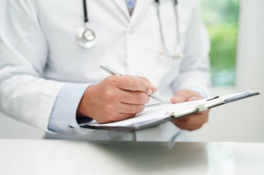Asyalı doktor, hastaları tedavi etmek için araştırma yöntemi ve teknikle ilgili belgeleri inceliyor..