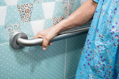 Asyalı yaşlı kadın hasta tuvalette tuvalet desteğini, tırabzan emniyet çubuğunu, hemşire hastanesinde güvenliği kullanıyor..