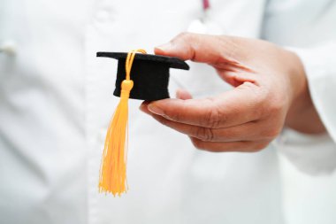 Hastanede elinde mezuniyet şapkası olan Asyalı kadın doktor. Tıp eğitimi konsepti..