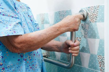 Asyalı yaşlı kadın hasta tuvalette tuvalet desteğini, tırabzan emniyet çubuğunu, hemşire hastanesinde güvenliği kullanıyor..