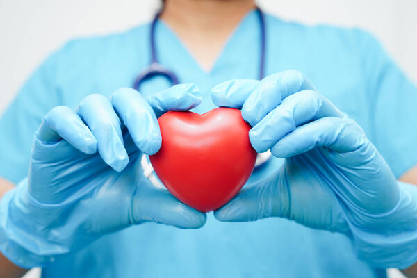Asian woman doctor holding red heart for health in hospital.