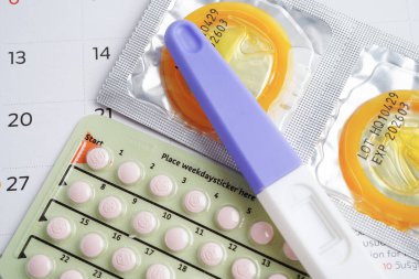 Doğum kontrol haplarıyla hamilelik testi ve takvimde kadınlar için prezervatif, yumurtlama günü.