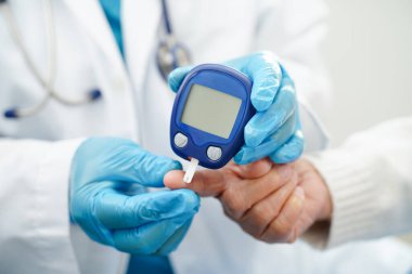 Diyabet tedavisinde kan şekeri seviyesini kontrol etmek için dijital glikoz ölçer kullanan Asyalı doktor.