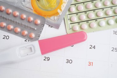 Doğum kontrol haplarıyla hamilelik testi ve takvimde kadınlar için prezervatif, yumurtlama günü.