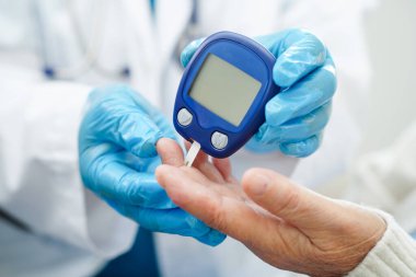 Diyabet tedavisinde kan şekeri seviyesini kontrol etmek için dijital glikoz ölçer kullanan Asyalı doktor.