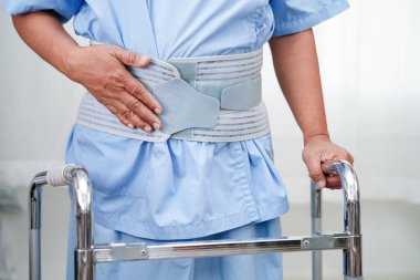 Asya baş ağrısı. Esnek destek kemeri takıp yürüteç takıyor..