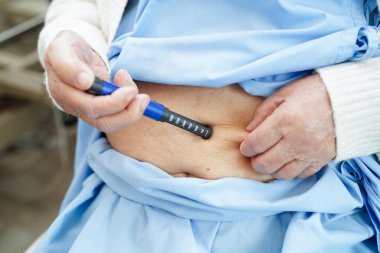 Diyabet tedavisi için karnına insülin iğnesi yapan Asyalı son sınıf öğrencisi kadın..